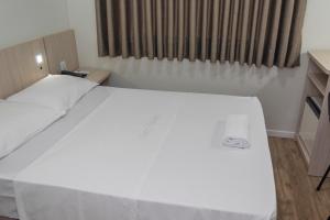 uma grande cama branca num quarto com uma janela em Hotel Vitoria - Itajaí em Itajaí