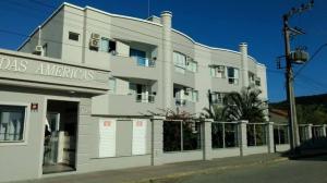 un edificio blanco con una valla delante en Apartamento de 2 quartos no Jardim das Américas- Bombinhas, en Bombinhas