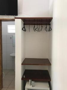 a bathroom with wooden shelves and a white wall at Pousada Tropical in Arraial d'Ajuda