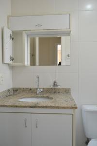 a bathroom with a sink and a mirror and a toilet at Aluga-se Apto 2 Quartos, sendo 1 suíte, 3 Ar cond. Mobília completa - Praia Grande Ubatuba/SP in Ubatuba