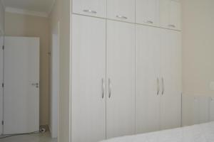 a white kitchen with white cabinets in a room at Aluga-se Apto 2 Quartos, sendo 1 suíte, 3 Ar cond. Mobília completa - Praia Grande Ubatuba/SP in Ubatuba +13 photos