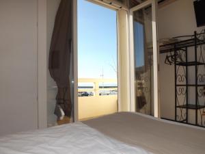 a bedroom with a bed and a window with a view at Hôtel Le Carnon in Carnon-Plage