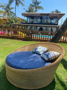 a wicker chair with two pillows sitting in a yard at Pousada Canto dos Encantos in Barra Grande