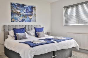 a bedroom with a large bed with blue pillows at Modern, Cosy & Convenient 3 bed 2 bath House WiFi Parking by Ark SA in Sheffield