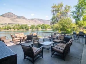 eine Terrasse mit Stühlen und Tischen neben einem Fluss in der Unterkunft Riverland Inn & Suites in Kamloops