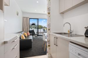 een keuken met een wastafel en een woonkamer met een bank bij Brookside Gem - Modern 2 Bedroom Apartment in Queenstown