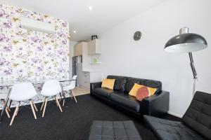 een woonkamer met een zwarte bank en witte stoelen bij Brookside Gem - Modern 2 Bedroom Apartment in Queenstown +6 foto's