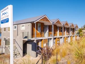 a row of houses on the beach with a sign at Lakeside Living - Modern 2-Bedroom Apartment in Queenstown