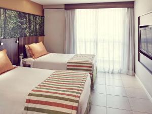 ノヴァ・イグアスにあるMercure Rio de Janeiro Nova Iguaçuのベッド2台と窓が備わるホテルルームです。
