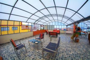 un patio con sillas, mesas y techo de cristal en Inka's Rest Hostel, en Puno