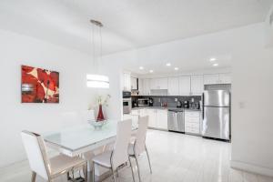 Sunny Isles Ocean Reserve Superb Condo Apartments في ميامي بيتش: مطبخ أبيض مع طاولة طعام وكراسي