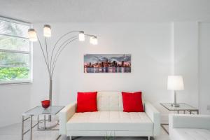 Sunny Isles Ocean Reserve Superb Condo Apartments في ميامي بيتش: غرفة معيشة مع أريكة بيضاء ووسائد حمراء