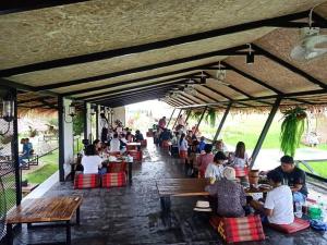 a group of people sitting at tables at a restaurant at ข้าวทุ่งเบ็ญจาโฮมสเตย์ in Ban Hat Phang