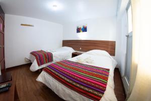 a bedroom with two beds with a colorful blanket at Inka's Rest Hostel in Puno