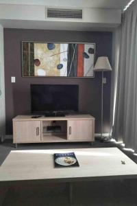 a living room with a tv and a table at 96 North Terrace Spa Apartment in Adelaide