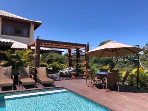 a patio with a table and umbrella next to a pool at Casa Praia do Forte - Piscinas naturais in Farol