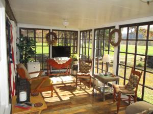 a living room with chairs and a tv and windows at Gorgeous cabin by river for 2, Princeton- I-77 in Princeton