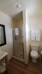 a bathroom with a toilet and a shower with towels at Kernville Inn in Kernville