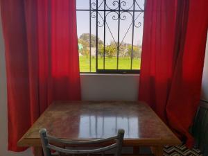 a wooden table in front of a window with red curtains at Los Naturales in Huaral