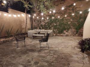 eine Terrasse mit 2 Stühlen, einem Tisch und Lampen in der Unterkunft Casona San Cayetano Suites & Lofts by Lunian in Guanajuato