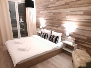 1 dormitorio con una pared de madera y 1 cama en New Grey Residence Apartament, en Târgu Mureș