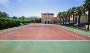 a tennis court in front of a building with palm trees at Hôtel Pyrène in Foix