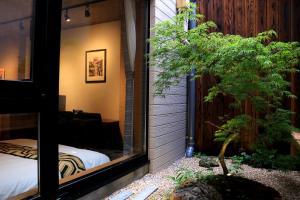 Blick auf ein Schlafzimmer aus einem Fenster mit einem Baum in der Unterkunft Hotel Traveling Bridge Nijojo in Kyoto