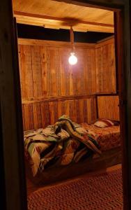 Cama pequeña en habitación con pared de madera en Al Khateem Art Hub en Baţīn
