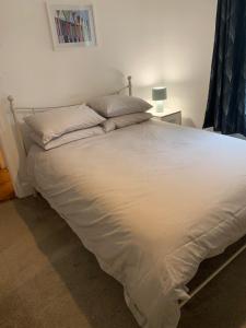 Una cama con sábanas blancas y almohadas en un dormitorio en Comfy flat in the heart of St Leonards, en St. Leonards