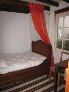1 dormitorio con 1 cama con cortina roja y ventana en Gite de Flandre, en Cassel