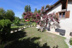 un jardin avec un arbre et des fleurs roses dans l'établissement Le Domaine Loft - Piscine - Jacuzzi - Parc, à Tullins