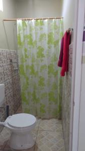 a bathroom with a shower curtain and a toilet at Rumanija's Airport Rooms in Zanderij