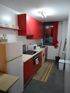 una cocina con armarios rojos y un aparato blanco en Apartamento completo, en Liérganes
