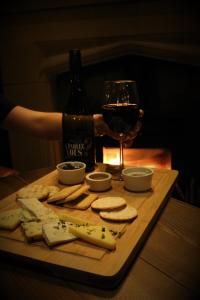 a person holding a glass of wine and a plate of cheese and crackers at The Bold Hotel; BW Signature Collection in Southport