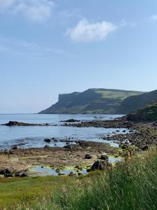 a beach with a body of water with mountains in the background at Ballycastle, Beachside Apartment in Ballycastle