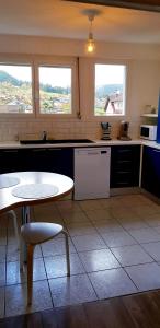 a kitchen with a table and a table and two windows at Le petit vosgien in Gérardmer