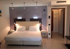 a bedroom with a large white bed with lights above it at Hotel L'Approdo in Pettenasco