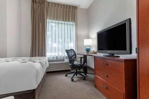 a hotel room with a bed and a desk with a television at Sleep Inn in Amherst