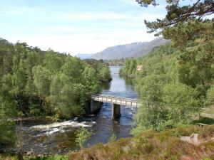 a bridge over a river in a valley at Ornum Cottage in Beauly