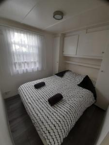 een slaapkamer met een bed met twee zwarte objecten erop bij Bospareltjes Luxe chalets Alleen voor recreatie in Oisterwijk