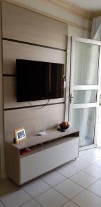 uma sala de estar com uma televisão de ecrã plano na parede em Village em Guarajuba