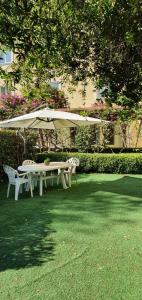 una mesa de picnic blanca y una sombrilla en el césped en Hotel Mediterraneo, en Qualiano