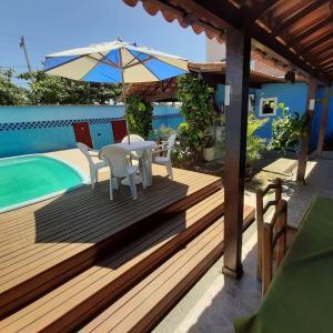 una terraza con mesa, sillas y sombrilla en Hostel Maré Mansa, en Cabo Frío