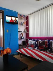 1 dormitorio con 1 cama y TV en la pared en Departamento de huéspedes Grijalva, en Ciudad de México
