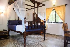 a bedroom with a canopy bed and a window at Laliguras Villa 200 Mts from candolim beach in Candolim