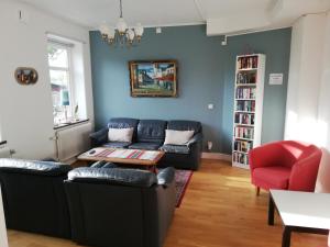 uma sala de estar com um sofá preto e uma cadeira vermelha em Hallandsåsen Hostel em Hjärnarp