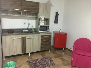 a kitchen with a microwave and a red refrigerator at Estudio dos Bonecos in Canela