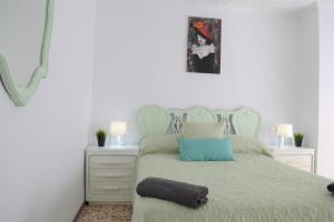 ein weißes Schlafzimmer mit einem Bett mit einem blauen Kissen in der Unterkunft Gran Notch in Alicante