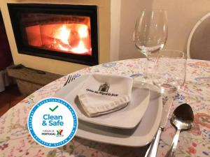 een tafel met een bord en wijnglazen en een open haard bij Quinta Sao Miguel de Arcos in Vila do Conde