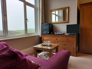 a living room with a couch and a table and windows at Boscastle House in Boscastle